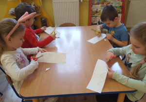 Dzieci wycinają koronę z papieru.